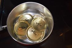 four empty beer cans sitting in a metal bowl on top of a stove burner