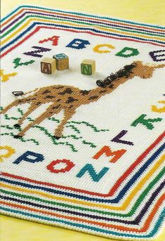 a cross - stitch afghan with wooden blocks and letters on it, featuring a dog