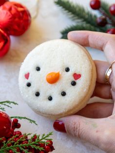 a person is holding a decorated snowman cookie