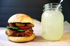 a chicken sandwich next to a jar of lemonade