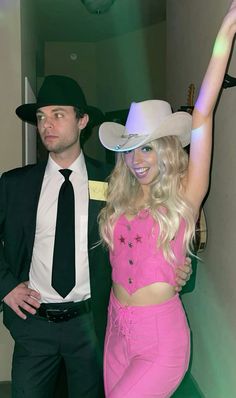 a man in a suit and tie standing next to a woman wearing a pink outfit