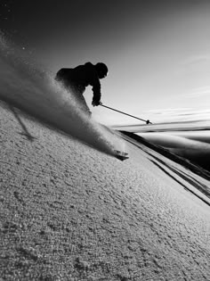 a man riding skis down the side of a snow covered slope with ski poles