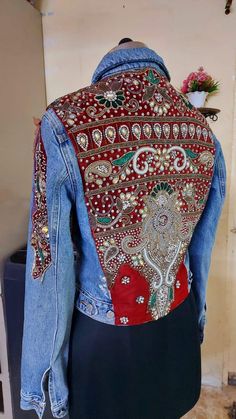 the back of a jean jacket with an elephant design on it, sitting on top of a mannequin