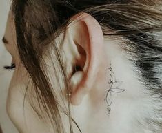 a woman's ear has a small flower tattoo on it