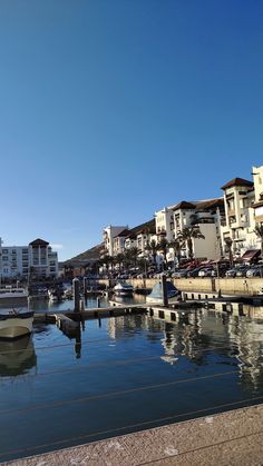 boats are parked in the water near buildings and docks on a clear blue sky day