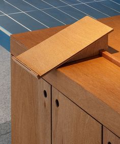 a close up of a wooden cabinet with blue tiles in the background