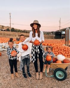 two women and three children standing in front of pumpkins