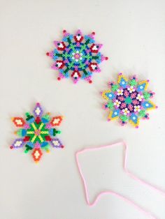 three different types of beaded snowflakes on a white surface