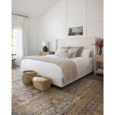 a large bed sitting on top of a rug in a bedroom next to a window