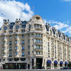 a very tall building with many windows and balconies on the top floor, in front of a blue sky