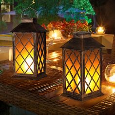 two lit lanterns sitting on top of a table next to each other with candles in them