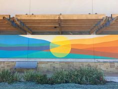 a large mural on the side of a building in front of a bench and flowers