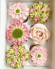 cupcakes decorated with pink and green flowers in a box