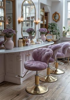 two purple chairs sitting on top of a wooden floor next to a counter with mirrors