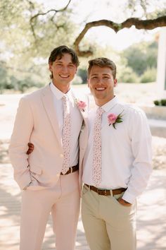 two men in white shirts and ties standing next to each other smiling at the camera