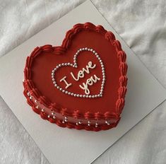 a red heart shaped cake with i love you written on it