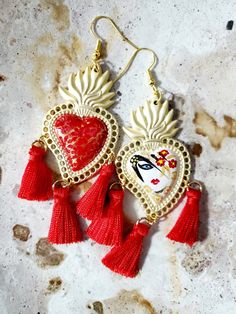 Beautiful hand painted earrings inspired by our Mexican culture, with an abstract face in red, black and gold, adorned tassels, are protected with several layers of jewelry varnish, improving the quality and durability of the earrings. These earrings are inspired by our Mexican culture and hand painted; They are the ideal gift because they combine with any outfit both day and night, enhancing the beauty of whoever wears them, attracting attention for being unique hand-painted pieces, the Ideal gift for Mother's Day and holidays. Features/ Product info Note: Each earring is hand painted, there are small differences between each pair, so each pair of earrings in this store is unique. The Main Material: Zinc Alloy (Gold) Color: Red -Large: 2 in  (Please see the photos, this design comes in tw Hand Painted Dangle Heart Earrings As Gift, Artistic Handmade Heart Earrings For Gift, Artistic Hand Painted Jewelry For Valentine's Day, Bohemian Hand Painted Heart Earrings As Gift, Bohemian Heart Earrings For Valentine's Day, Bohemian Earrings For Valentine's Day, Bohemian Nickel-free Earrings For Valentine's Day, Mexican Earrings, Gold Chandelier Earrings