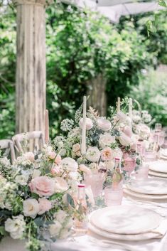 an outdoor table set with white and pink flowers