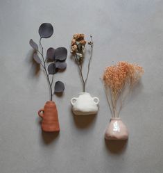 three ceramic vases with flowers and leaves on a gray surface, one in the shape of a bear