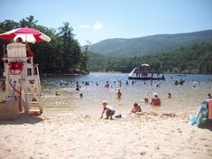 many people are on the beach and in the water at this time, there is a life guard tower