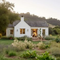 a small white house sitting on top of a lush green field