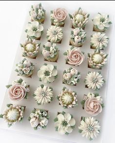 cupcakes decorated with flowers and greenery on a white tray, ready to be eaten