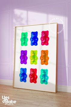 a framed photo with gummy bears on it in front of a purple wall and hardwood floor