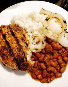 a white plate topped with meat, beans and rice