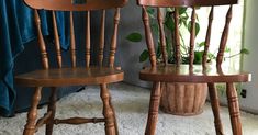 two wooden chairs sitting next to each other in front of a potted plant on the floor