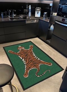 a tiger rug in the middle of a kitchen with black cabinets and countertops