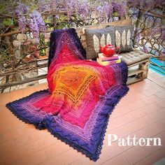 a crocheted blanket sitting on top of a wooden bench next to a potted plant