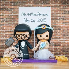 a wedding cake topper with a bride and groom holding hands in front of a brick wall