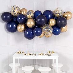 a white table topped with blue and gold balloons next to a wall mounted art piece