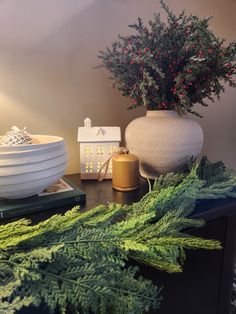 a table topped with two vases filled with plants and other decorating items on top of a wooden table