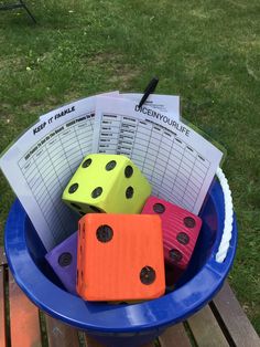 four dices in a blue bowl on a wooden table with some papers and pen