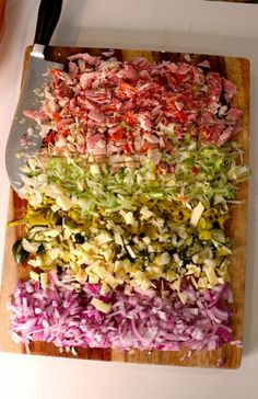 chopped up vegetables are on a cutting board with a large knife next to the cut up cabbage