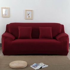 a red couch sitting on top of a carpet covered floor next to a white wall