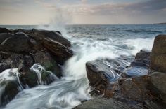 the waves are crashing on the rocks by the water's edge in this photo