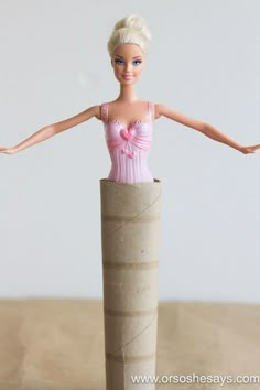 there is a doll that is sitting in a tube on the table with her arms stretched out