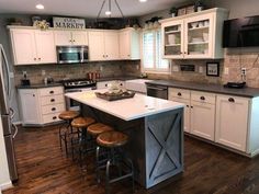 a large kitchen with white cabinets and wooden floors is pictured in this image, there are stools at the center of the island