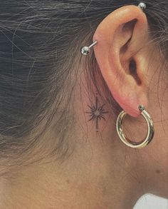 a woman's ear has a spider tattoo on it