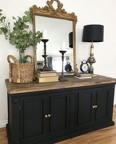 a large mirror sitting on top of a wooden dresser next to a lamp and vase