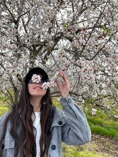 a woman is standing under a flowering tree