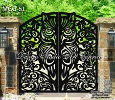 an ornate iron gate with flowers and trees in the background