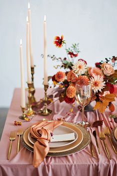 the table is set with candles, plates and napkins for an elegant dinner party