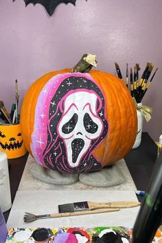 a pumpkin decorated with an image of a ghost on it's face, surrounded by other halloween decorations