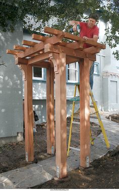 a man standing on top of a wooden structure in the middle of a yard next to a tree