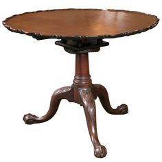 a wooden table with an ornate design on the top and base, sitting against a white background