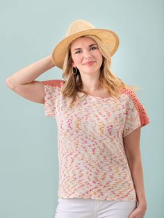 a woman wearing a straw hat and white pants with her hands on her head, posing for the camera