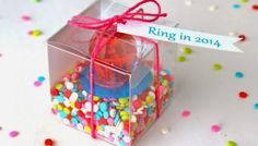 a clear box filled with candy and sprinkles next to a sign that says ring in 2014